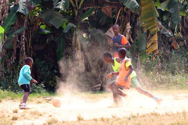 Enfants jouant au football dans la poussière