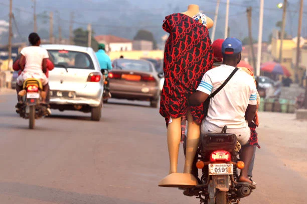 Passager d'une moto tenant un mannequin habillé