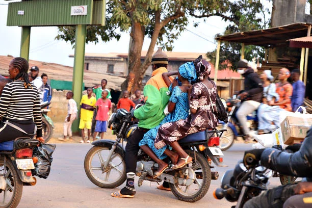 Moto-taxi transportant des passagères dans une rue animée